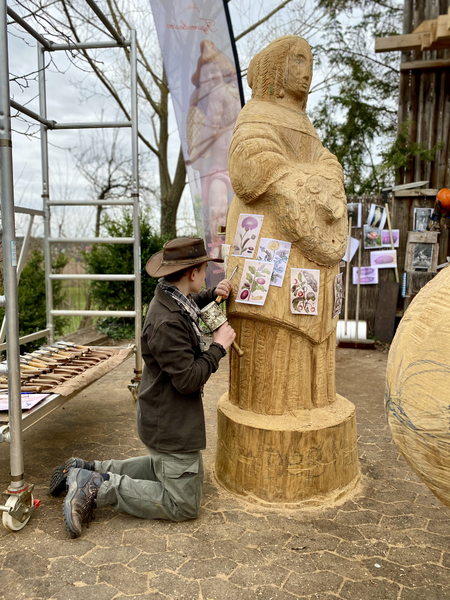 Praktikant der Werkstatt für Figurenbeuten Anton (14) schnitzt Blumen und Insekten in den Mantel der Insektenforscherin