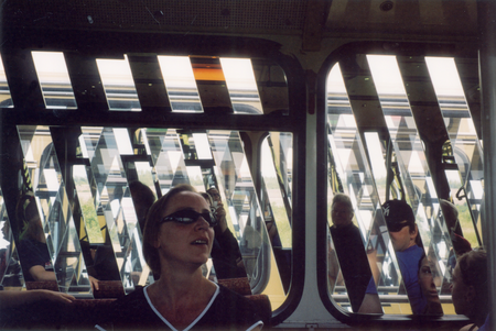 People reflected through two lined up buses, 2023 - photo: Susanne Ahner